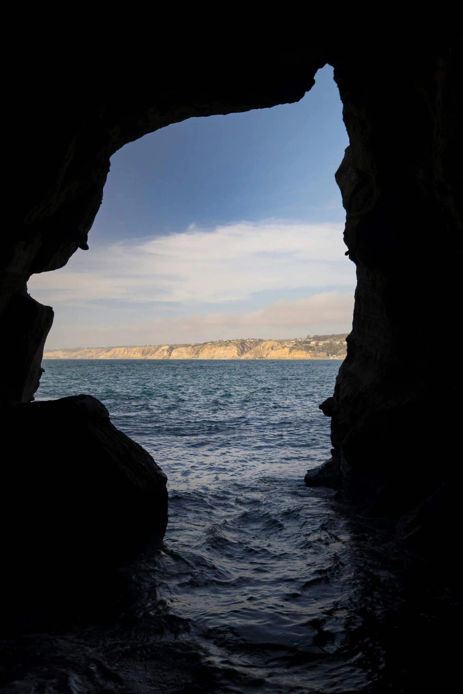 a view of the ocean through a dark cave