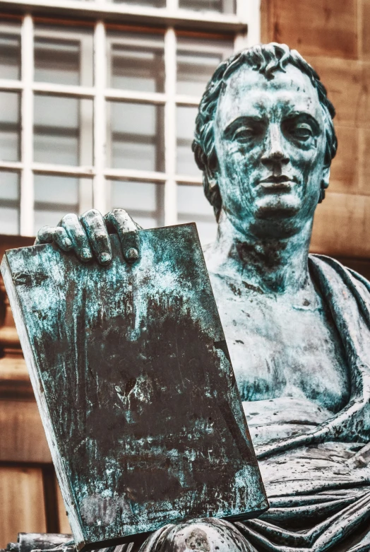 a man holds up a drawing in front of a statue