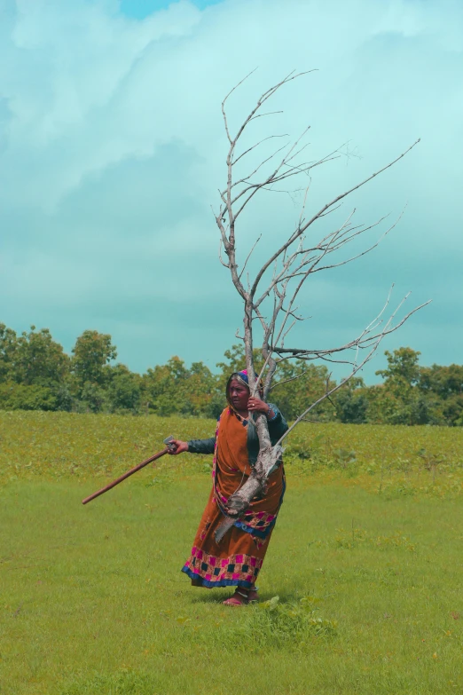 an indian woman wearing colorful clothing is holding a stick in her hand