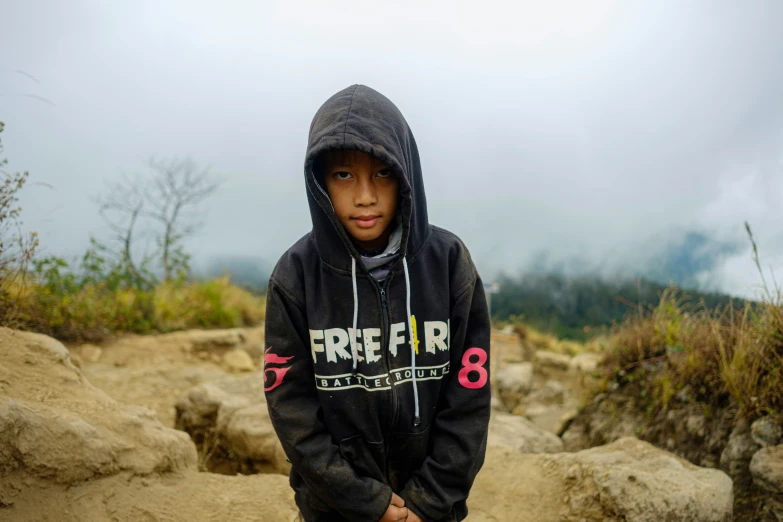 the boy in the hoodie stands on a dirt path