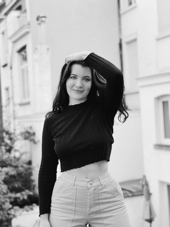 a woman is posing on the sidewalk by some buildings