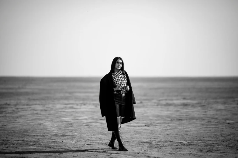 a woman standing in the sand looking back