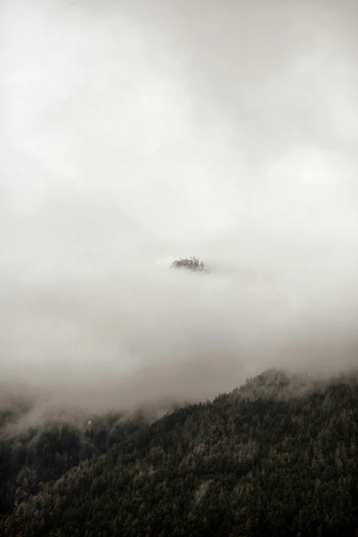 fog covers mountains with a house on top