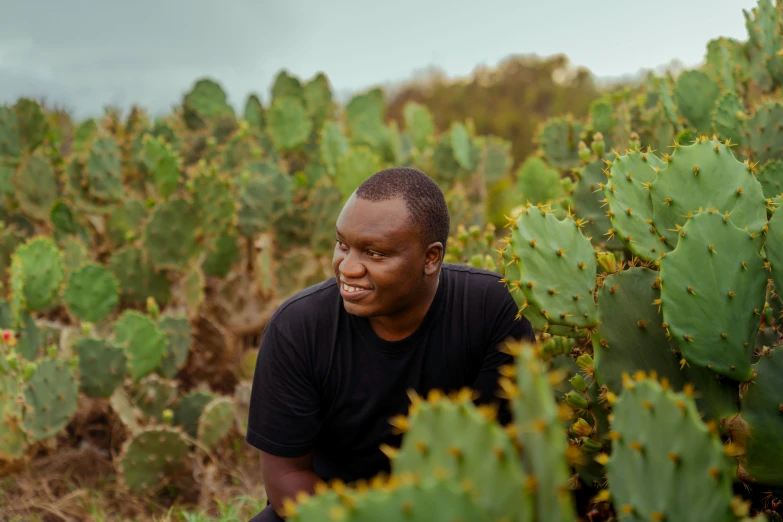 a man standing between green plants in a field