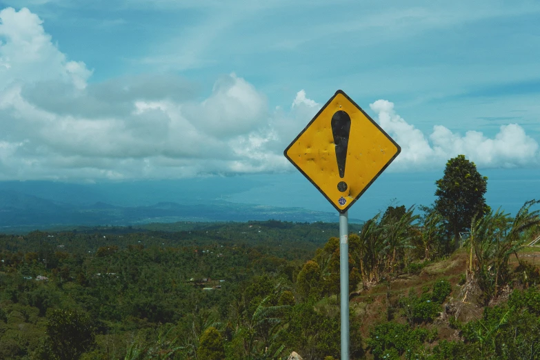 there is a yellow and black sign on the hill