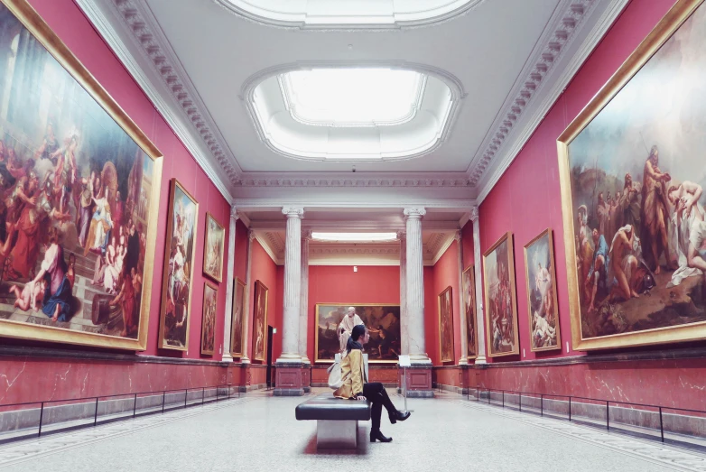 a woman sitting on a bench in a long room