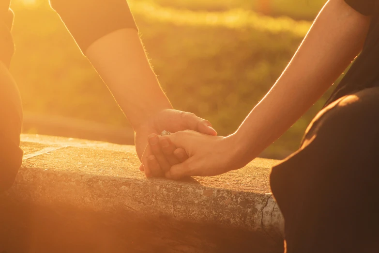 close up of two people holding hands outdoors