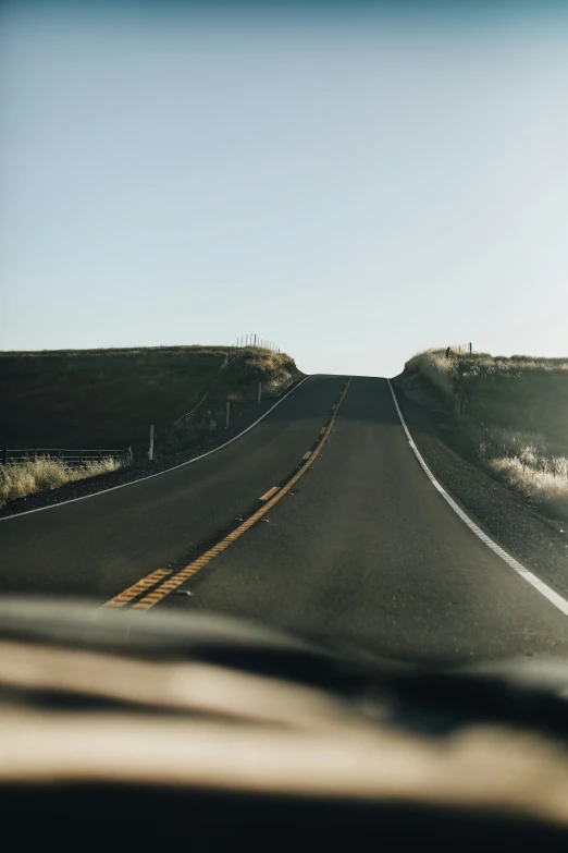 a close up view from the driver's seat of a car traveling down a deserted country road