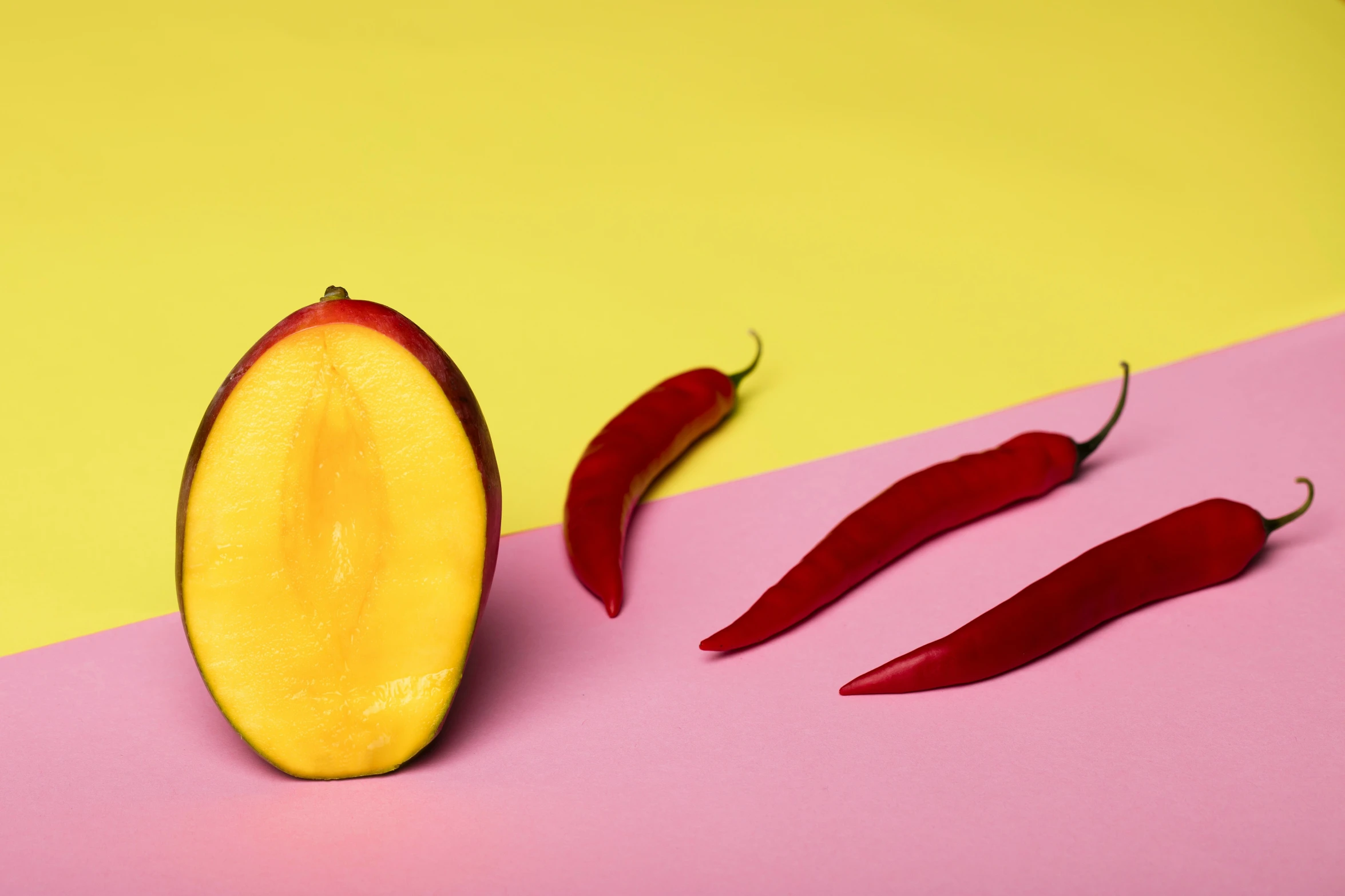 three chili peppers are sitting on a yellow and pink surface