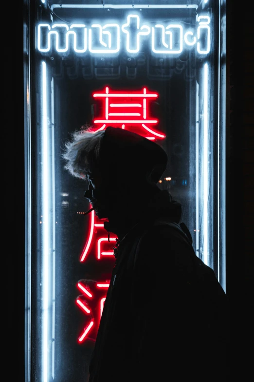 man standing in front of neon advertit and a black building