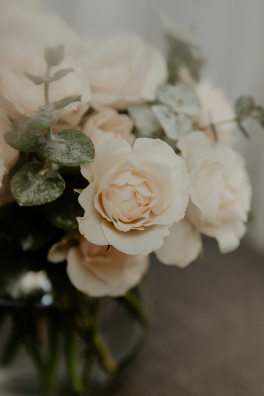 roses and leaves are arranged in a glass vase