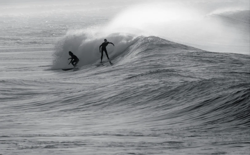 two surfers ride waves while the light is hitting them