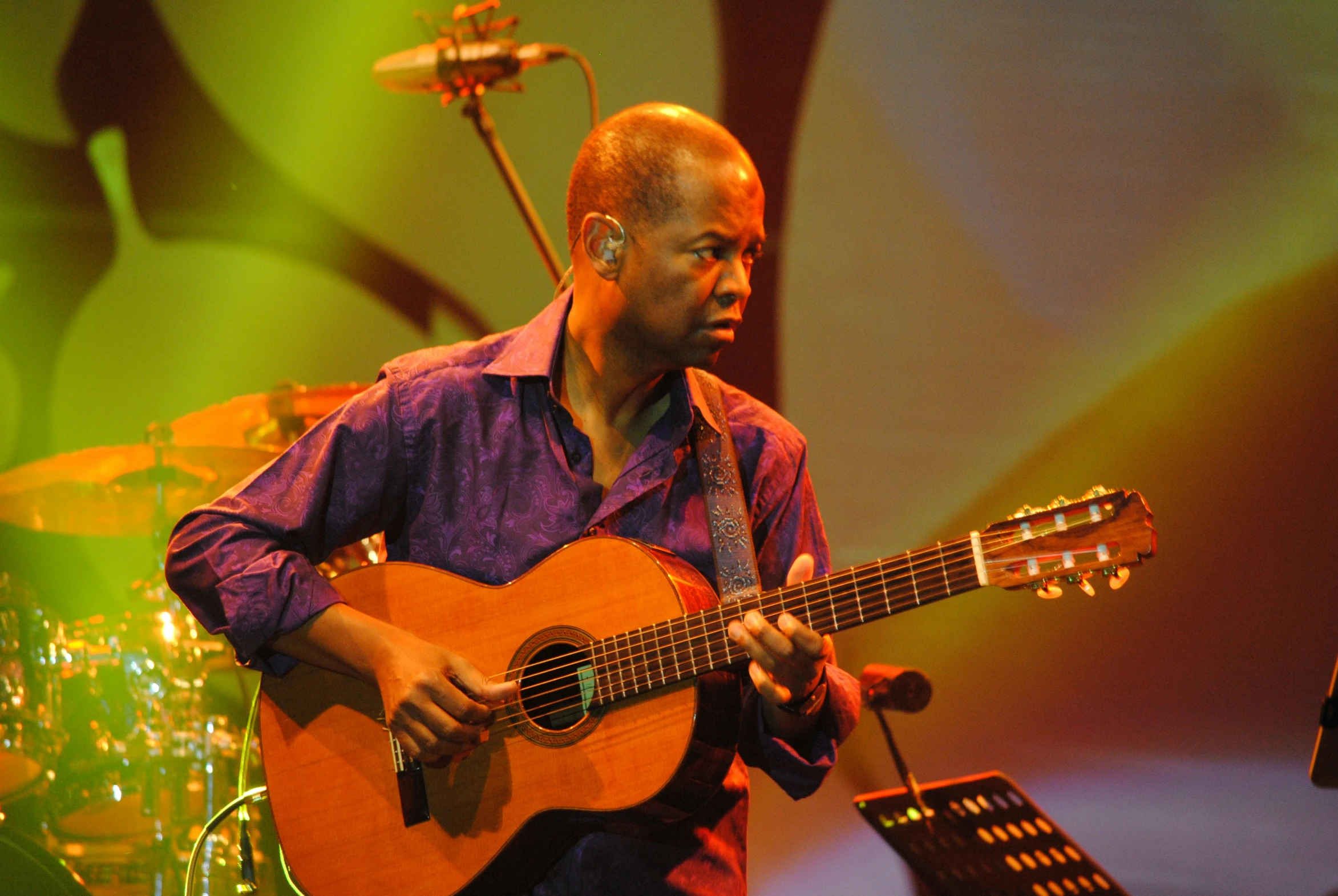 man with blue shirt playing a guitar on stage