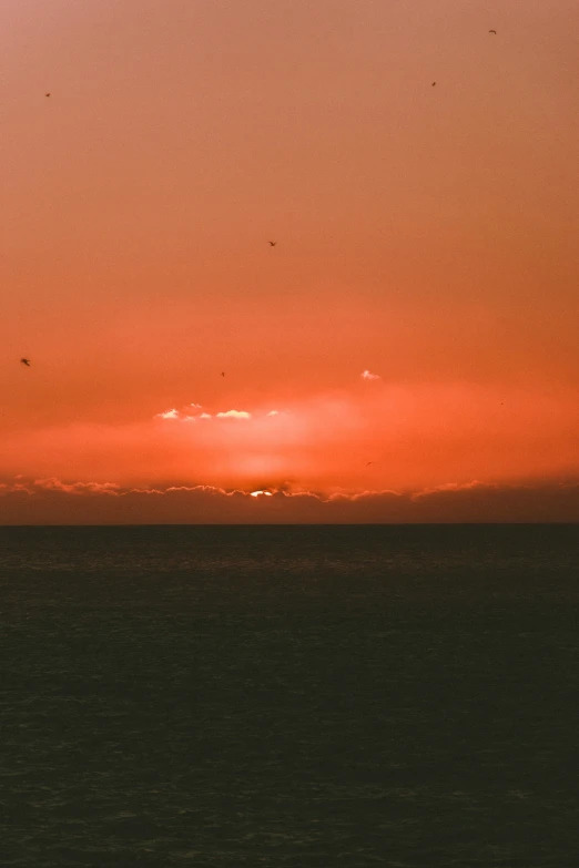 a boat is sitting on the water near the setting sun