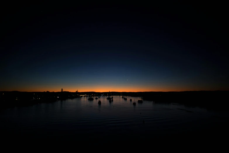 boats are in the water at night as the sun sets