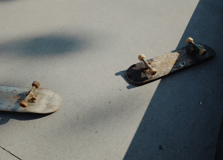 a couple of skateboards on a street with shadows on the ground