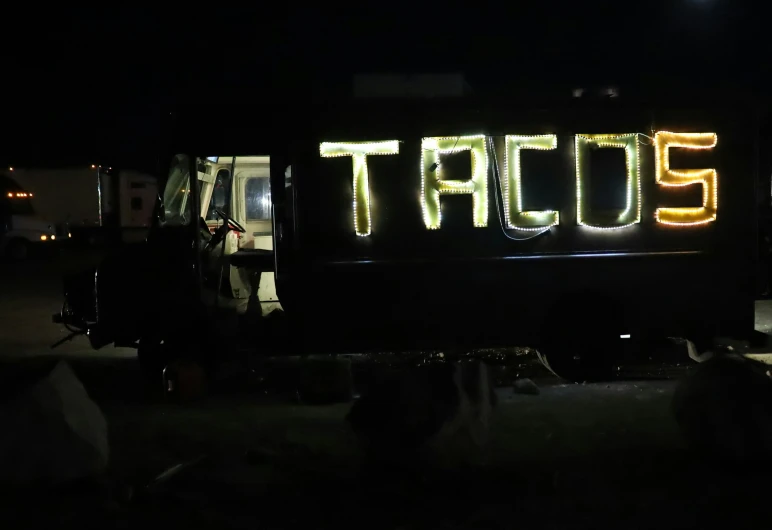 the back end of a truck with a neon sign on it