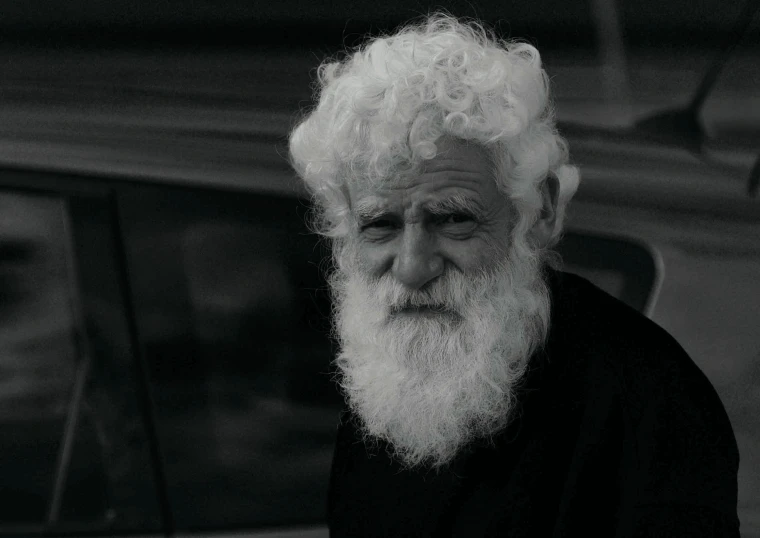 a man with white hair and beard looking in a car window