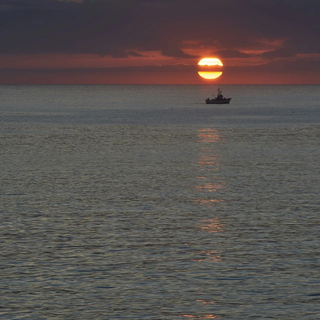 a boat is on the open ocean during sunset