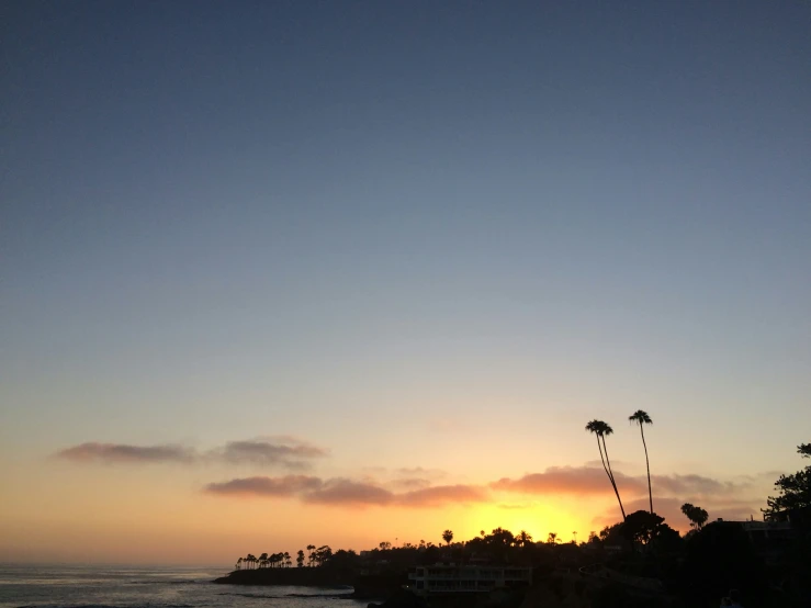 a sunset with trees and beach and water