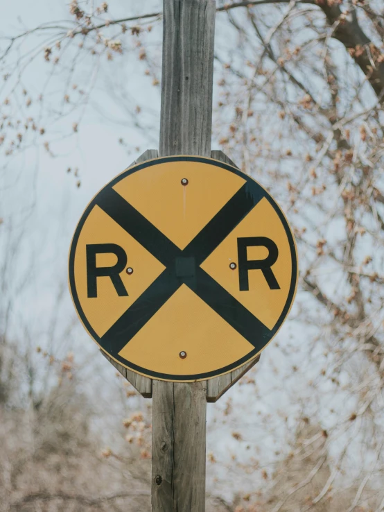 a railroad sign hanging from the side of a wooden pole