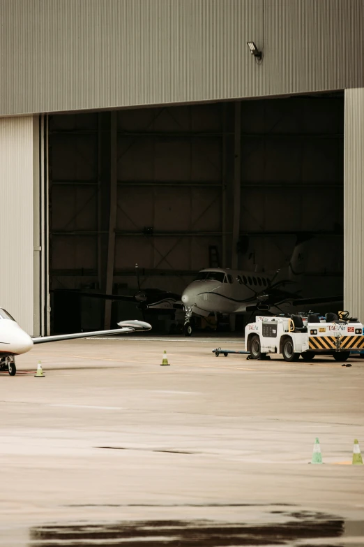 airplane sits parked in front of hangar where a truck is unloading