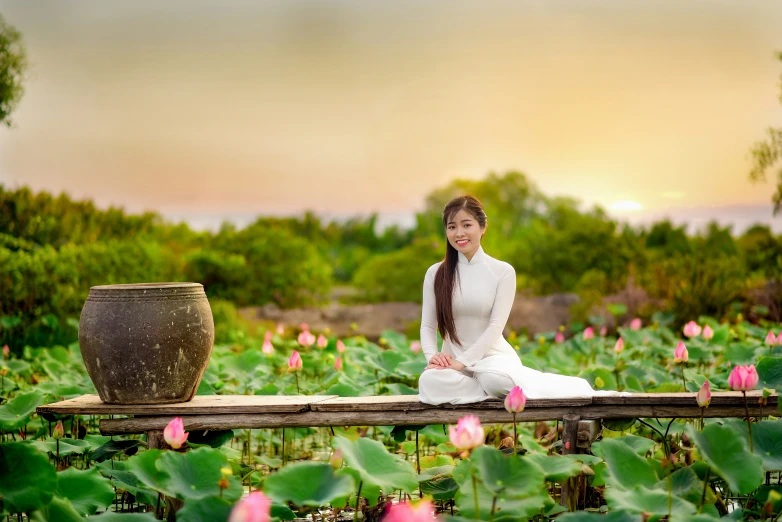 a woman sitting on top of a wooden bench surrounded by flowers