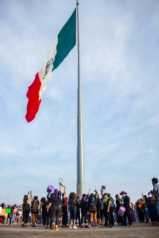 a group of people in various countries gather around a flag pole