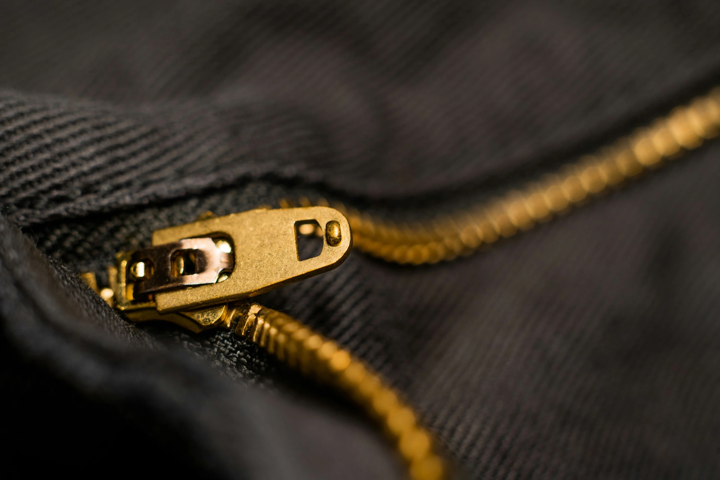 a gold zipper with black fabric with gold metal fittings