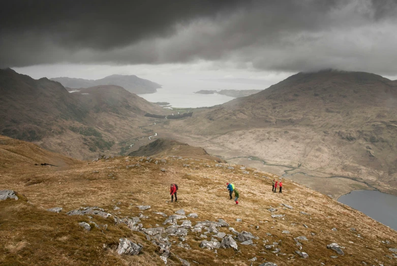 a group of people hiking up a grassy hill