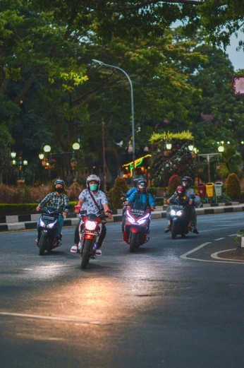 three bikers on roadway near city lights