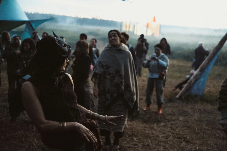 people sitting in a grassy field, some holding onto kites