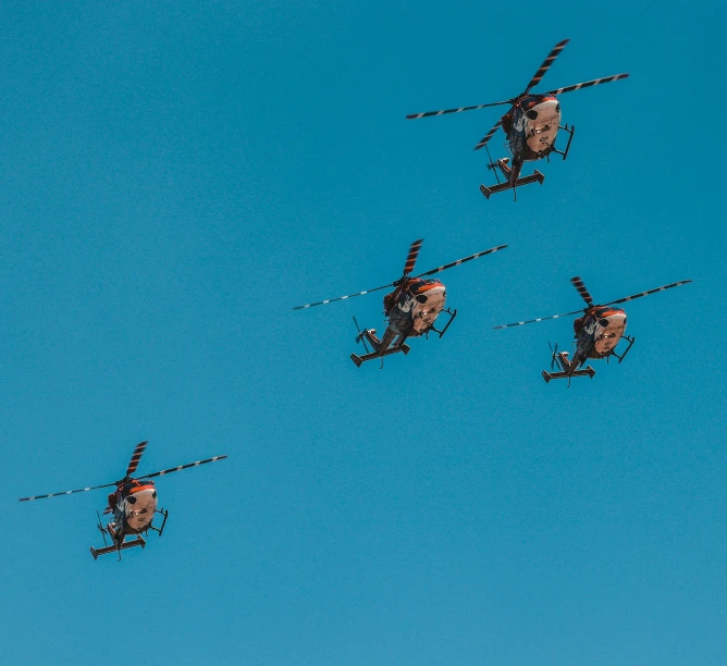 three air planes flying in the sky with one helicopter upside down