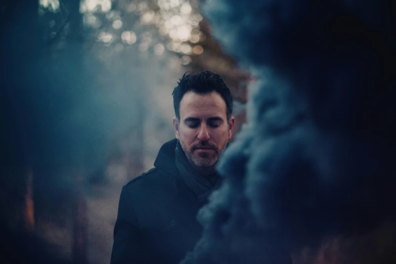 a man standing by some smoke on a dark night