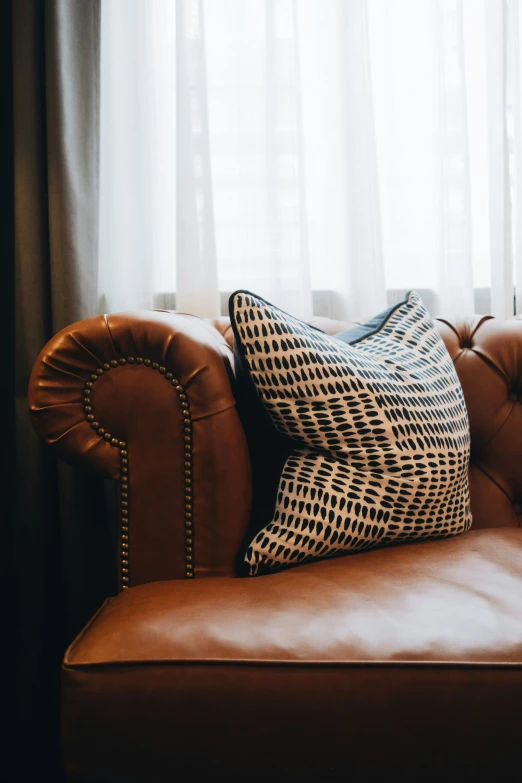 a couch with a large throw pillows and a brown leather upholstered back