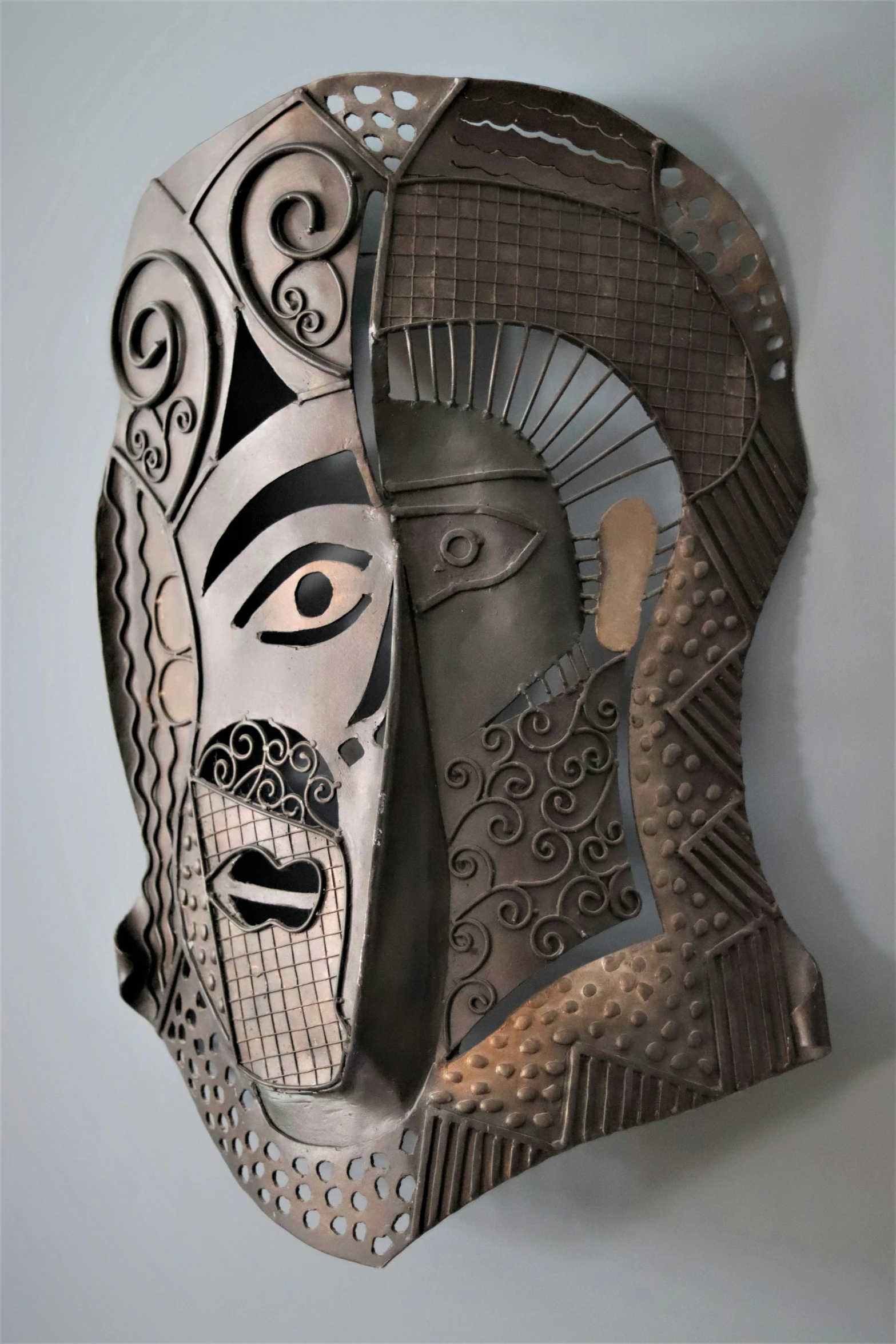 a mask is displayed on a wall with intricate carvings