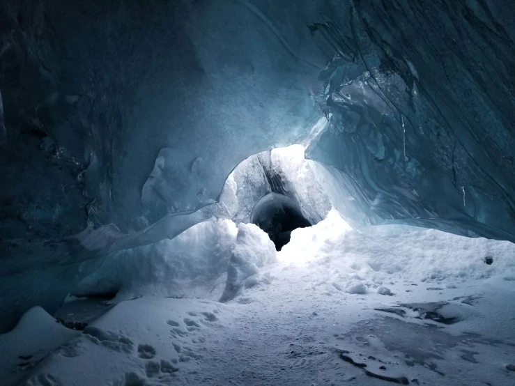 a dark room with snow in the center and a doorway to the cave