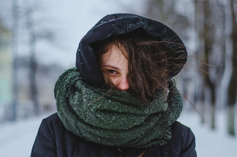 a woman wearing a black jacket with a green scarf on