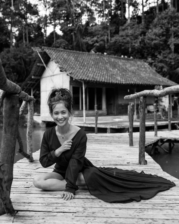 a woman wearing a dress is sitting on a dock