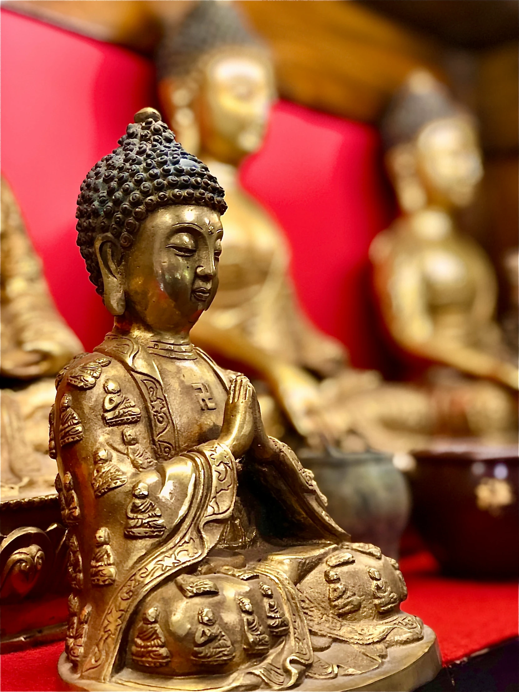 a golden buddha statue sits near some red seats