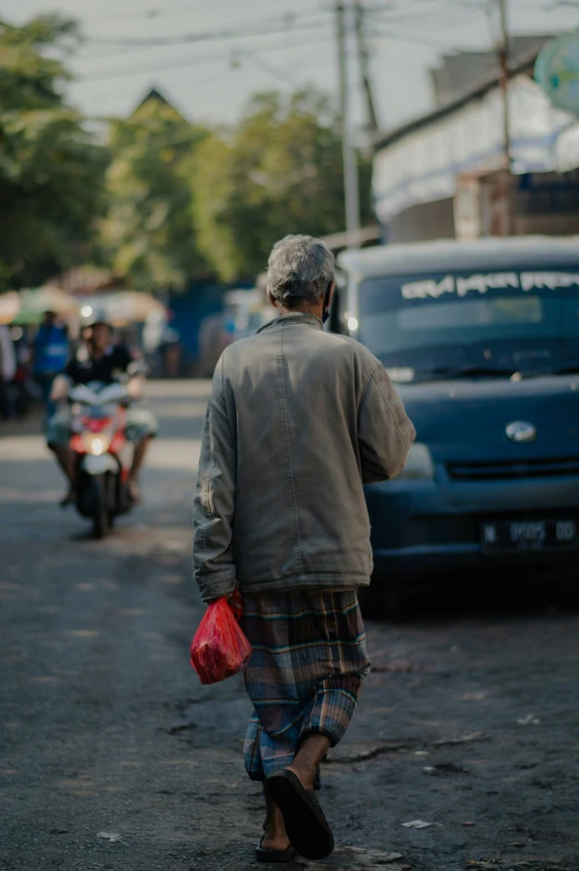 man walking down street with parked cars and motorcycle