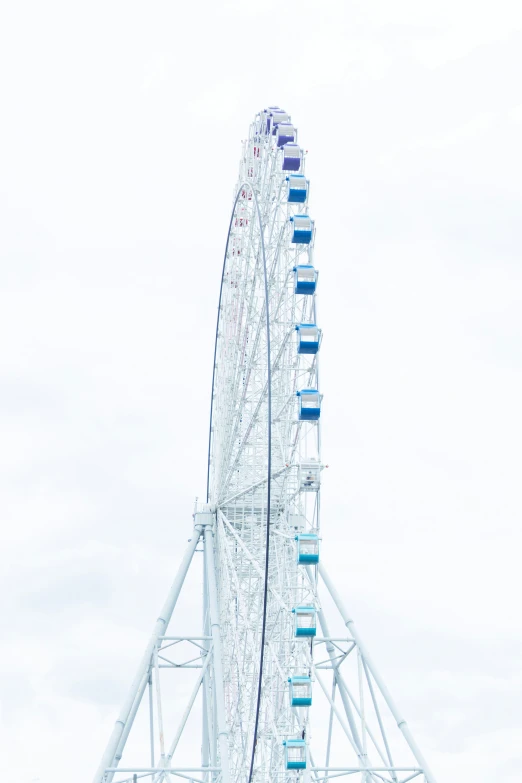 the ferris wheel is white and blue against the sky