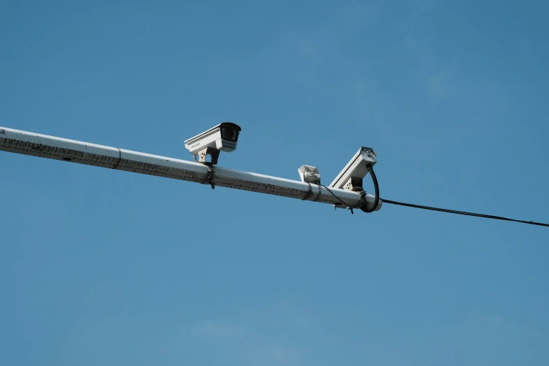 two surveillance cameras mounted on an overhead wire