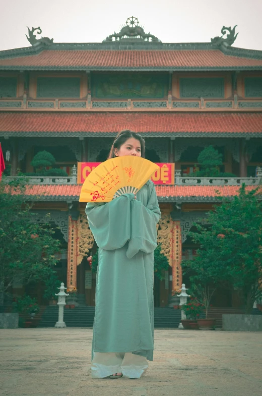 a woman with a green and yellow kimono holding a yellow fan