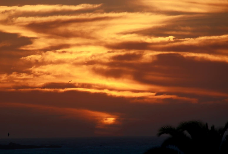 a bright orange sunset over the ocean and the sky