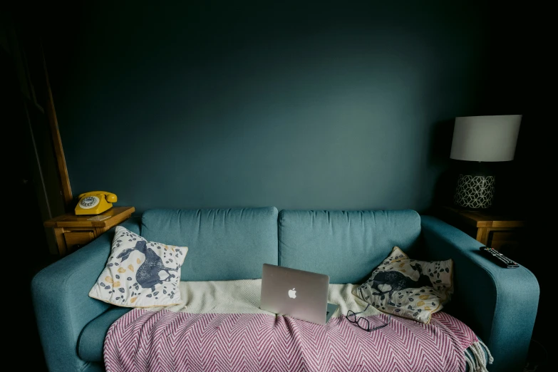 the couch has many pillows on it, along with an empty laptop computer