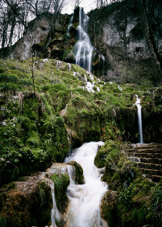 a waterfall on a rocky hillside with lush green plants
