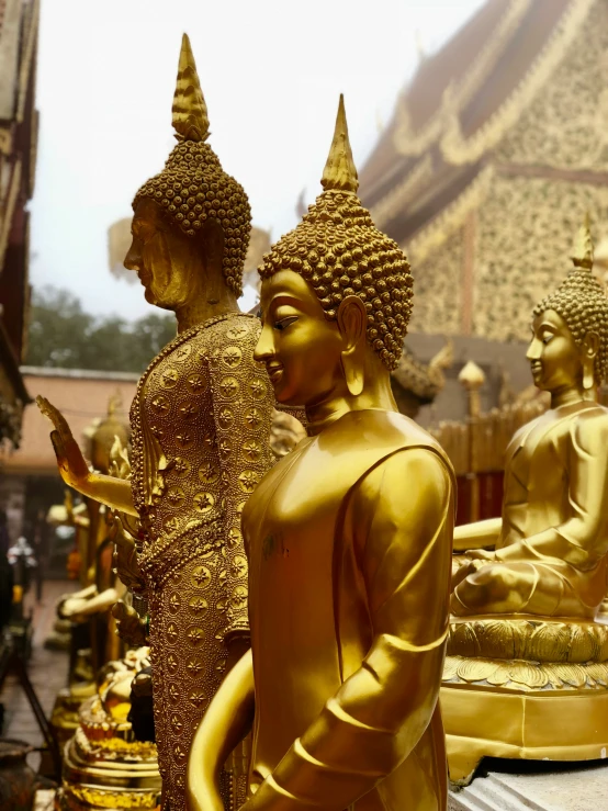 gold buddha statues sitting near a statue of a god