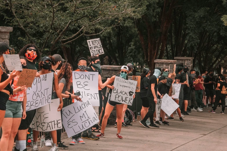 group of protesters carrying protest signs in front of trees