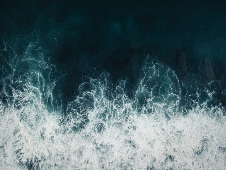 an aerial view of crashing waves in the water